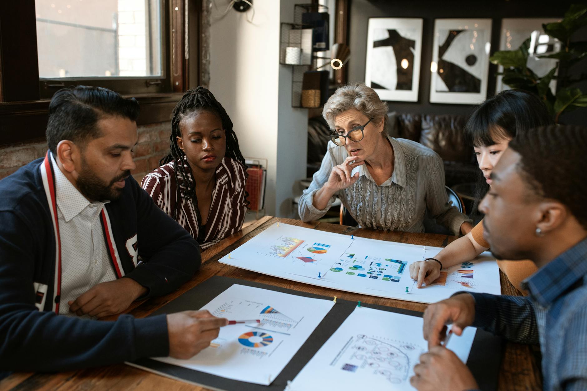 Small team around a table reviewing printed budget charts and figures