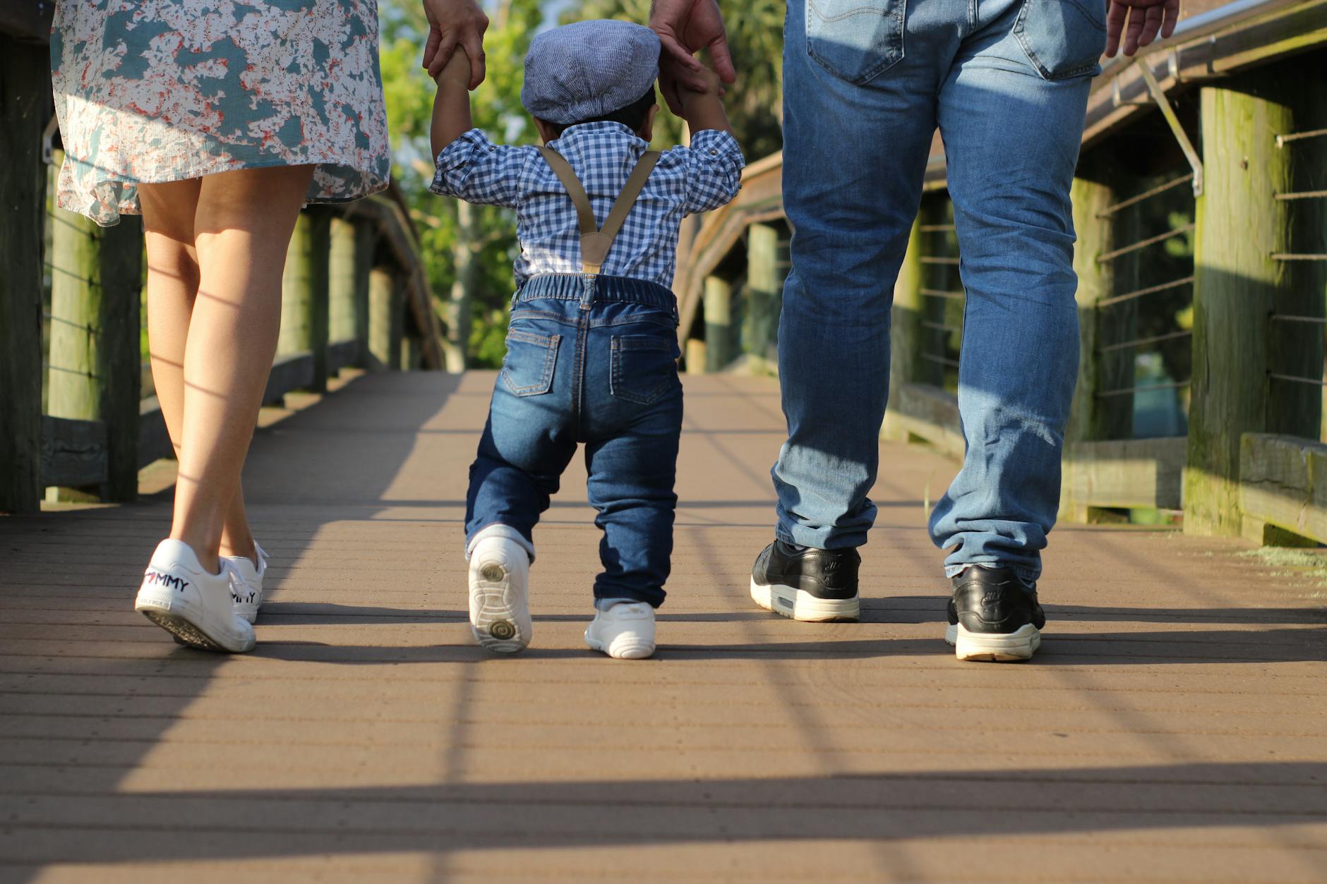 Padres caminando de la mano con un niño pequeño por un paseo de madera en Florida