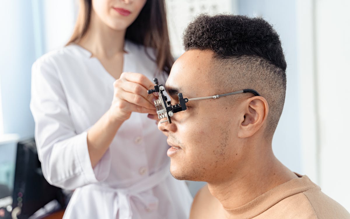 Optometrista colocando un armazón de prueba a un paciente durante un examen de la vista