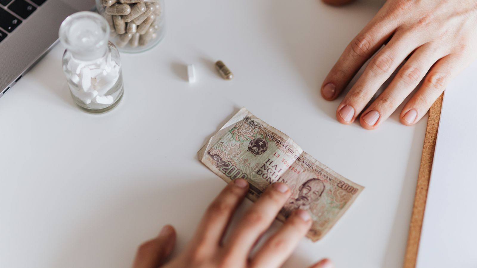 Adulto mayor con dinero y medicamentos sobre la mesa, representando el ahorro en costos de la Parte D con la Ayuda Adicional