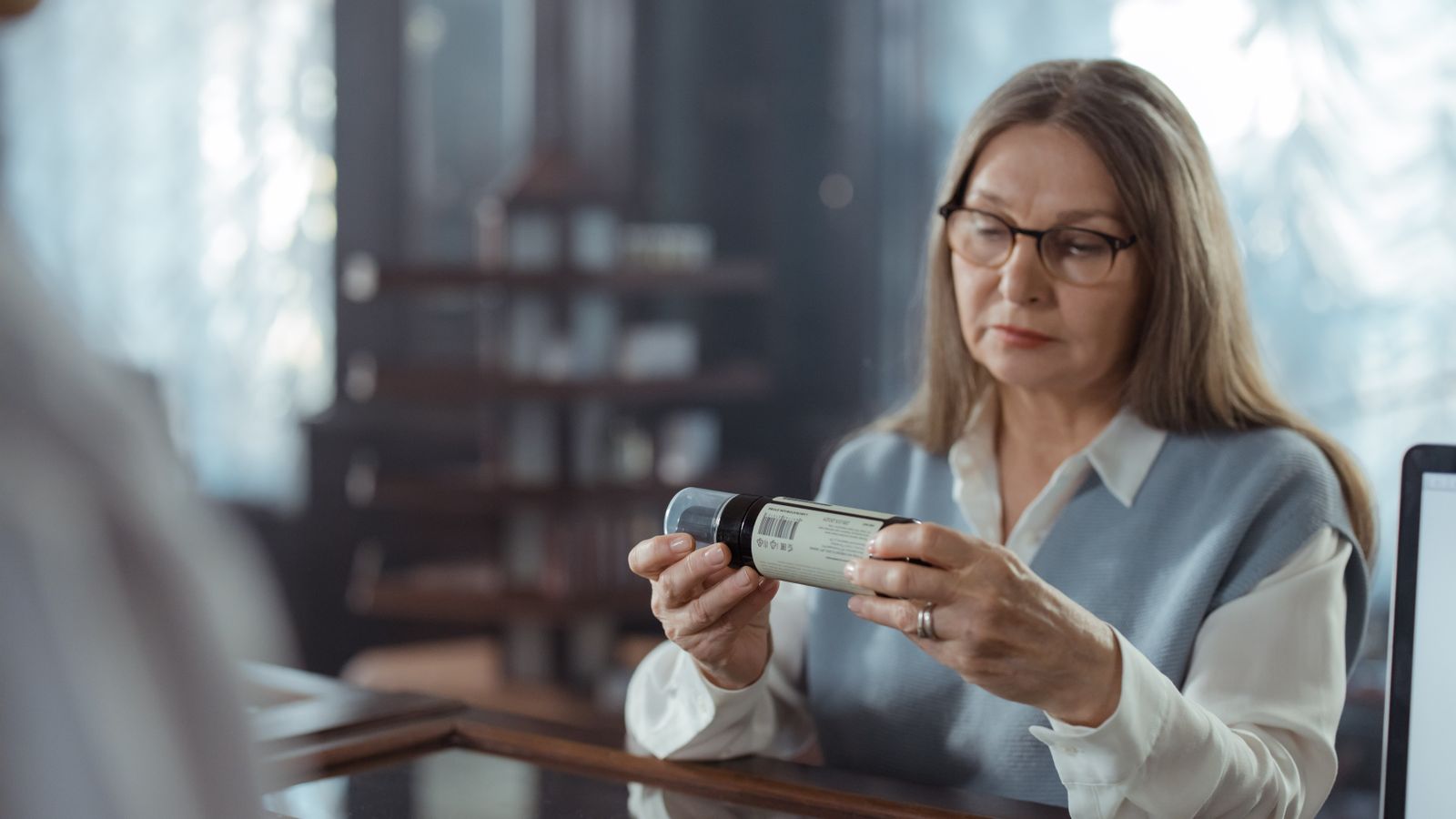Medicare beneficiary reading the label on a high-cost specialty prescription bottle