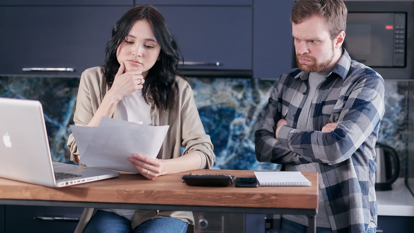 Couple at a kitchen table comparing health insurance costs with documents and a laptop