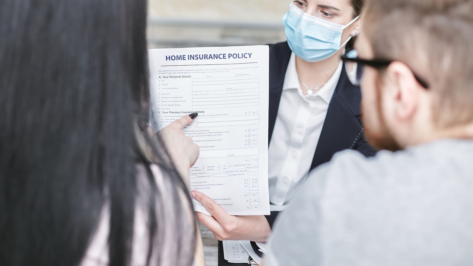Insurance agent explaining health coverage options to a couple across a meeting table