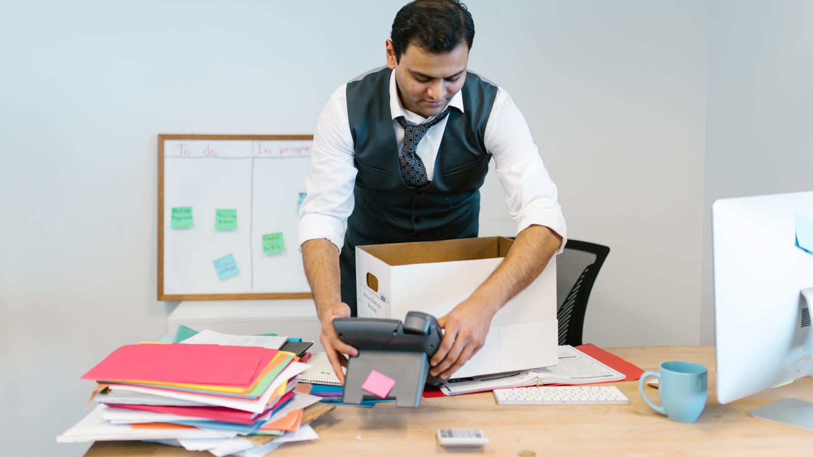Employee packing personal items from a desk after leaving a job with employer health coverage